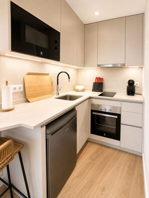 A compact kitchen with a dishwasher, oven, and a microwave above the stove. - A cozy and bright apartment, perfect for an unforgettable getaway (Torrox- costa)
