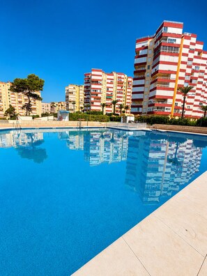 Piscina com superfície de água azul cristalina, cercada por edifícios residenciais com varandas.