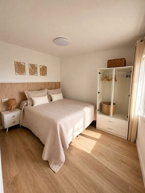 Quarto com cama, mesas de cabeceira, guarda-roupa e luminária no teto.