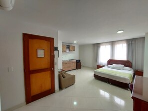 Habitació d'hotel amb llit, sofà, escriptori, petita cuina i bany.
