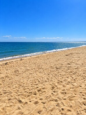Ein Sandstrand mit Fußspuren, die zum Wasser führen.