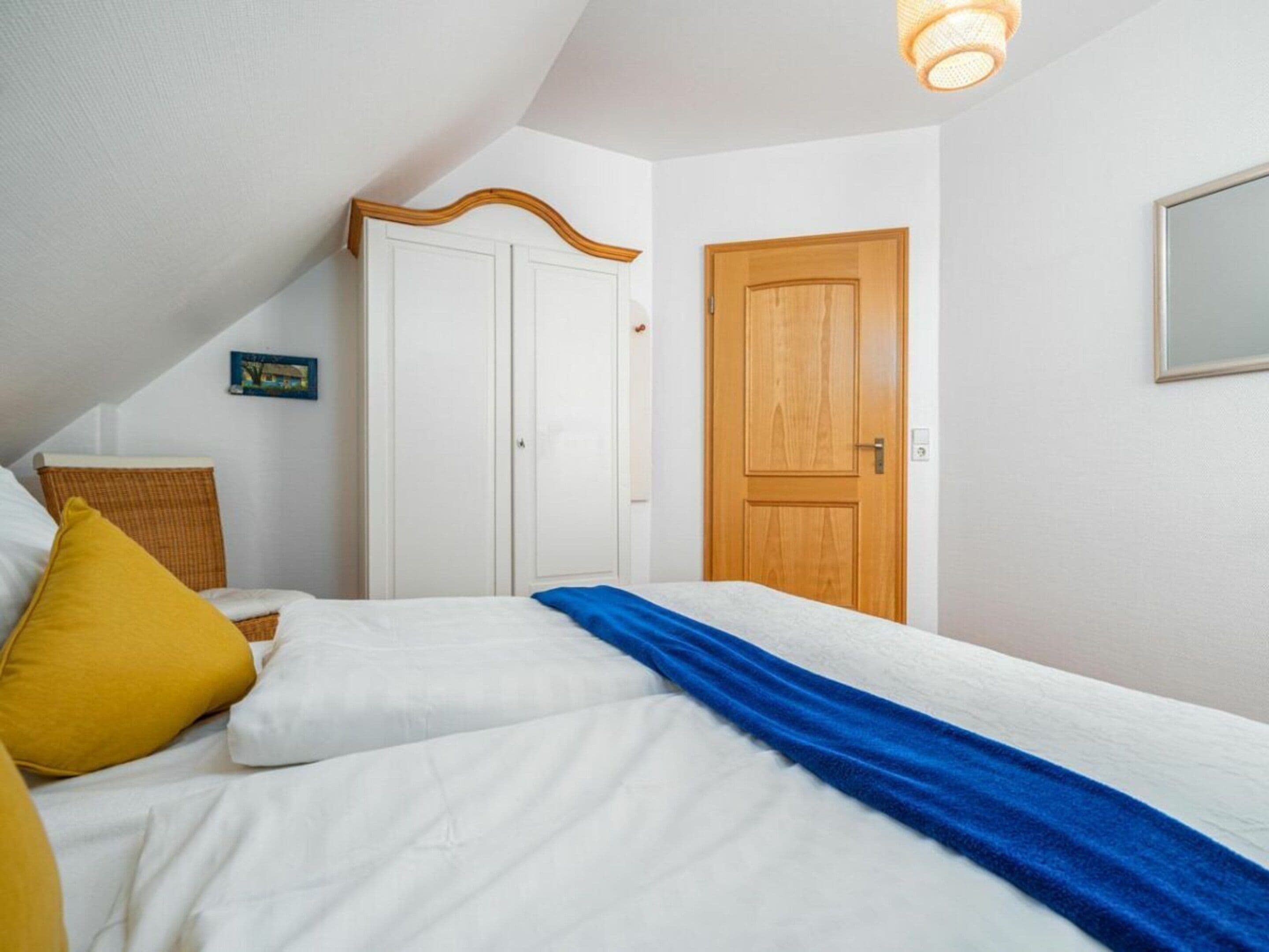 A bedroom with a bed, a wooden door, and a white wardrobe.