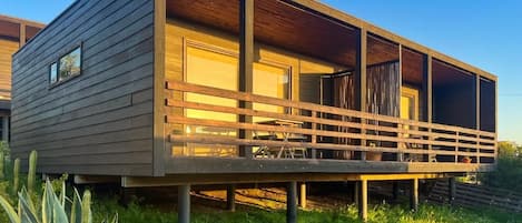 A modern house with a wooden deck and a covered outdoor area.