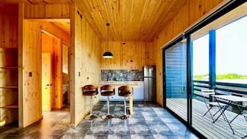A wooden interior with a kitchen, bar area, and large sliding glass doors leading to an outdoor deck.