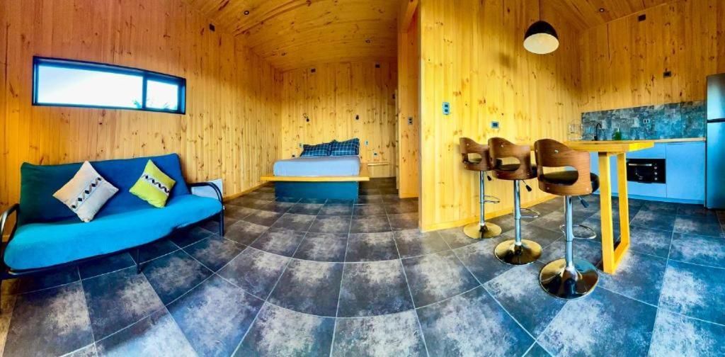 A wooden interior with a sofa, a bed, and a dining area.