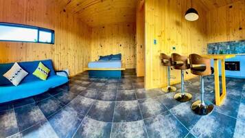 A wooden interior with a sofa, a bed, and a dining area.