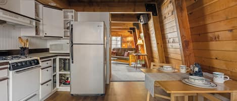 Una cocina con estufa, microondas, refrigerador y armarios de madera.
