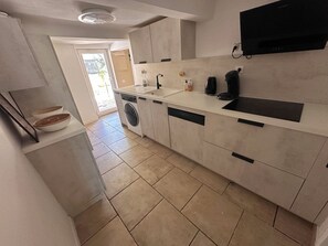 A modern kitchen with a built-in washing machine, a sink, and a flat-screen TV mounted on the wall.