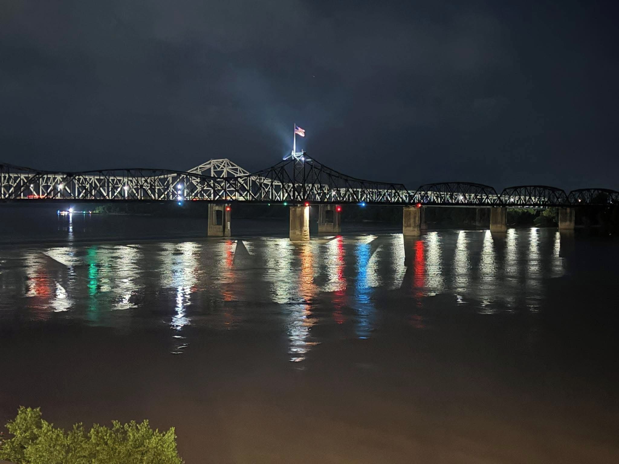 Una vista notturna di un ponte con le luci riflesse sull'acqua.