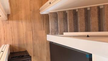 A compact kitchen with a built-in dishwasher, a wooden floor, and a staircase with beige carpeting.