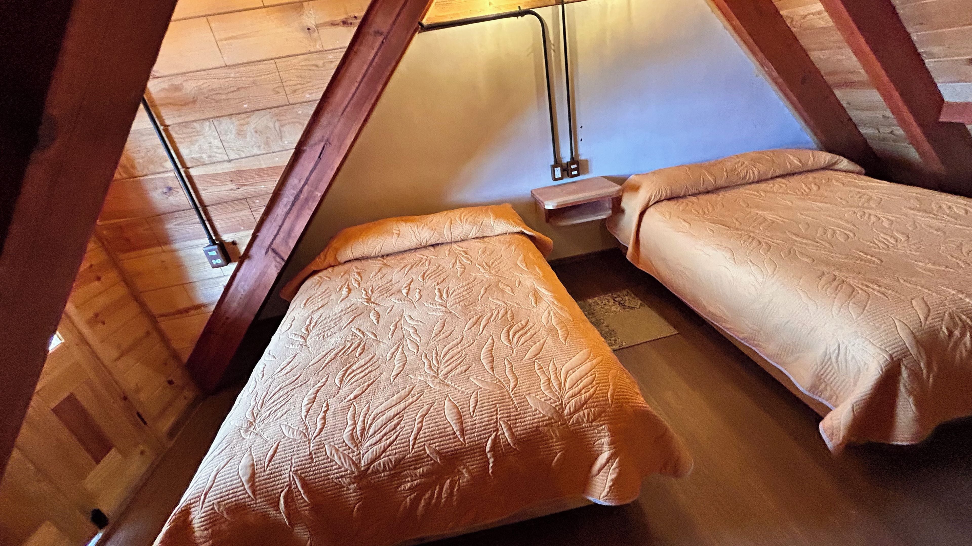 Una habitación con dos camas, vigas de madera y techo inclinado.