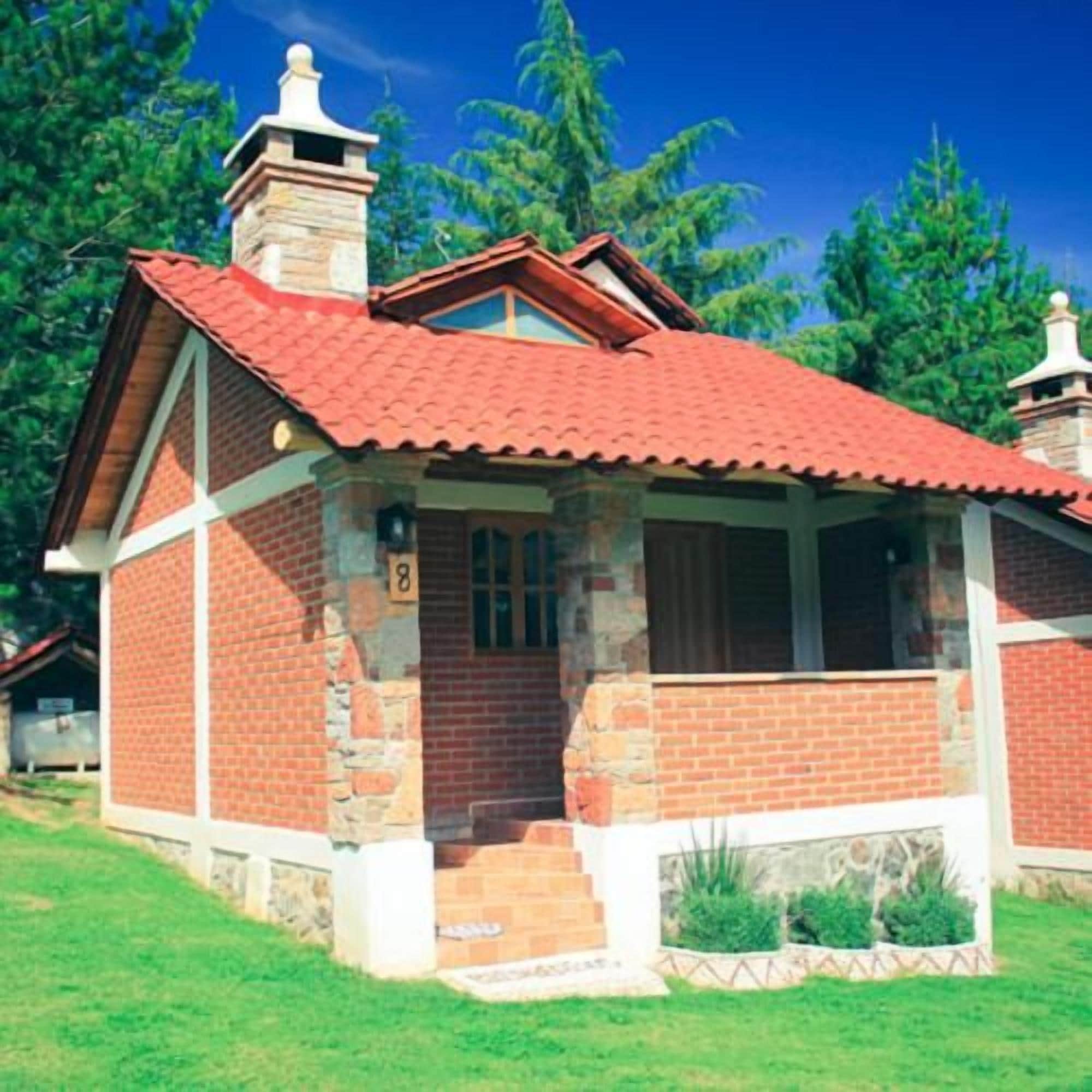 Una casa de dos pisos con techo de tejas rojas, paredes de ladrillo y chimenea de piedra.