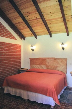 A bedroom with a wooden ceiling, a brick wall, a bed with a red blanket, and two wall-mounted lights. - Cabañas Rincón Escondido By GEstores (Huasca De Ocampo)