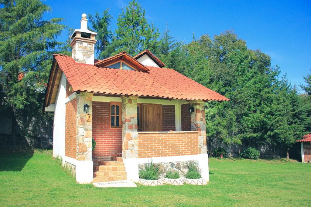 A small brick house with a red-tiled roof, a chimney, and a porch.