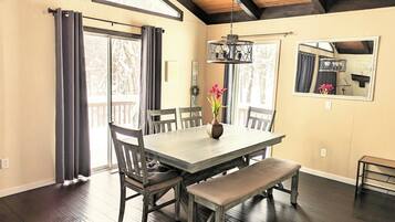 Une salle à manger avec une table en bois, des chaises, un banc et un vase rempli de fleurs.