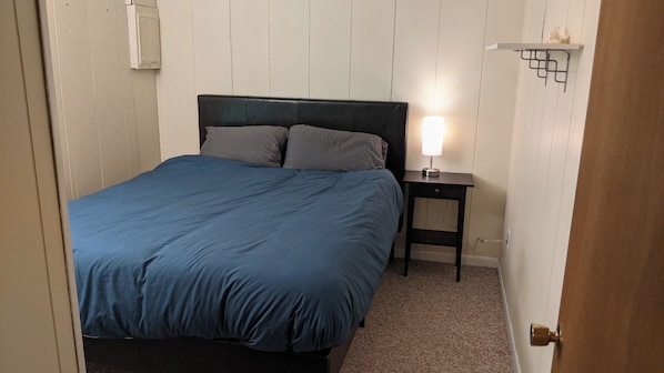 Une chambre à coucher avec un lit, une table de chevet avec une lampe et une porte.