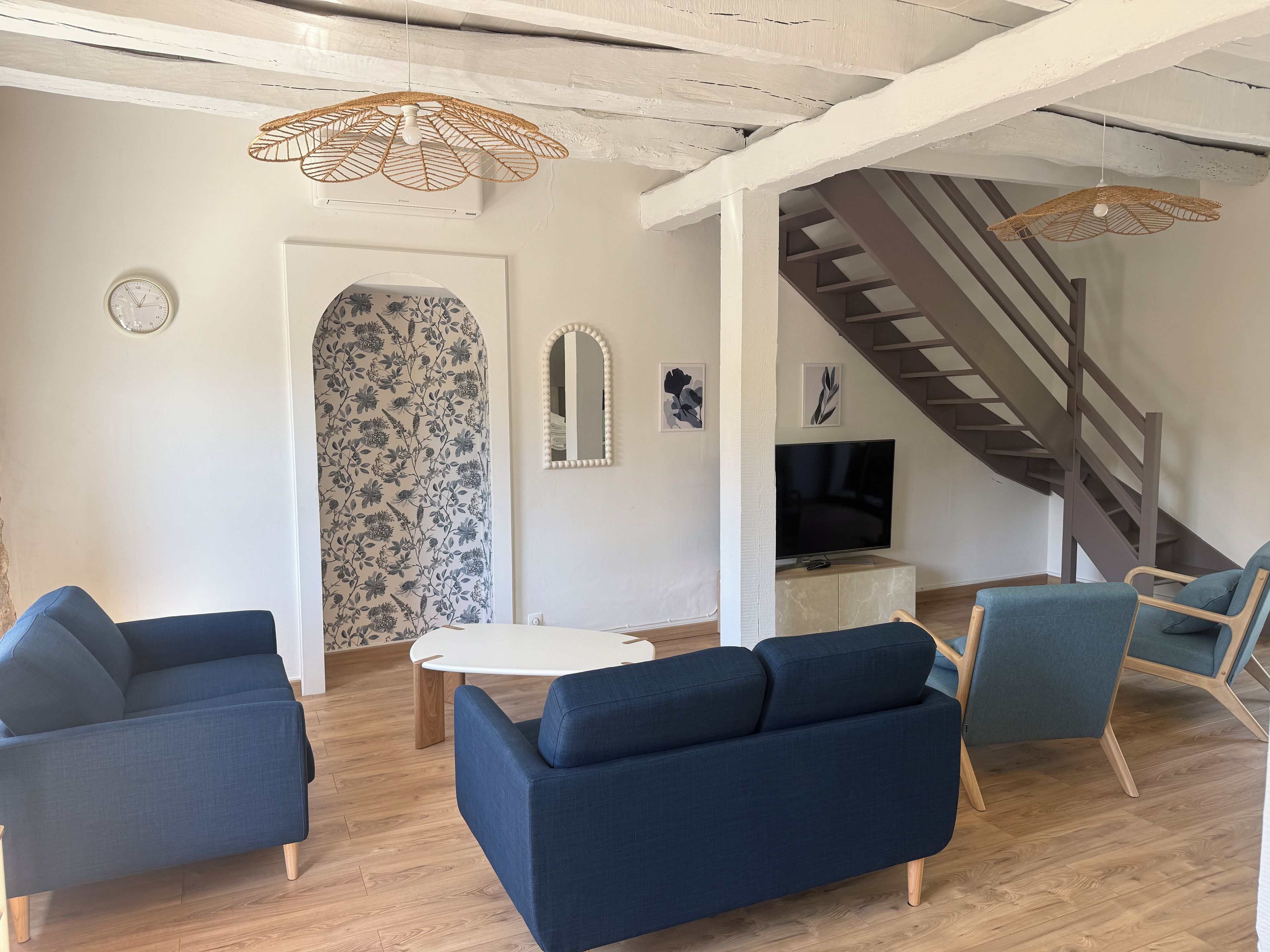 A living room with a sofa, chairs, a TV, and a staircase.