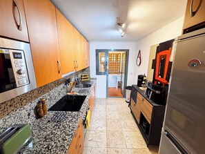 A kitchen with granite countertops, wooden cabinets, a stainless steel refrigerator, and a built-in oven. - Beautiful modern Apartment with GYM (Estepona)