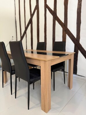Una mesa de comedor con cuatro sillas, detalles de madera y tapicería negra.