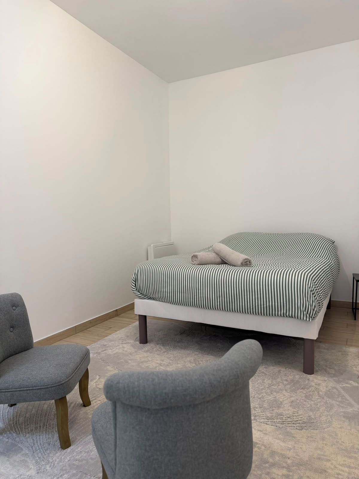 Quarto com cama, duas cadeiras e radiador.