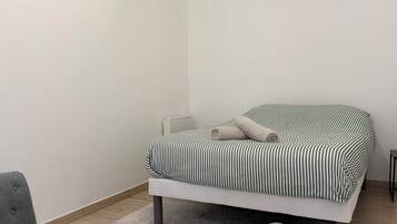 Quarto com cama, duas cadeiras e radiador.
