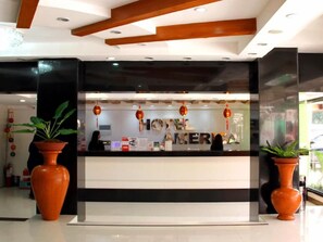 A hotel reception desk with a black and white color scheme, potted plants, and a sign reading 'HOTEL AMERICA'. - Fave Hotel Angeles City (Angeles City)