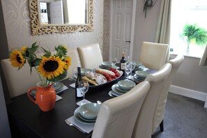 A dining table set with plates, glasses, a bottle, and a vase with sunflowers. - The Trafalgar (Scarborough)
