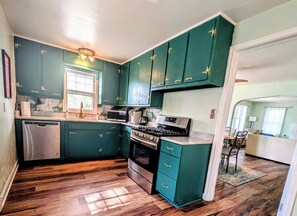 A kitchen with teal cabinets, a dishwasher, a stove, and a microwave.