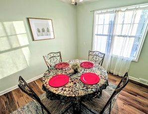 A dining area with a round table, four chairs, red plates, and a small potted plant. - Sunset View Retreat in Central Location (Omaha)