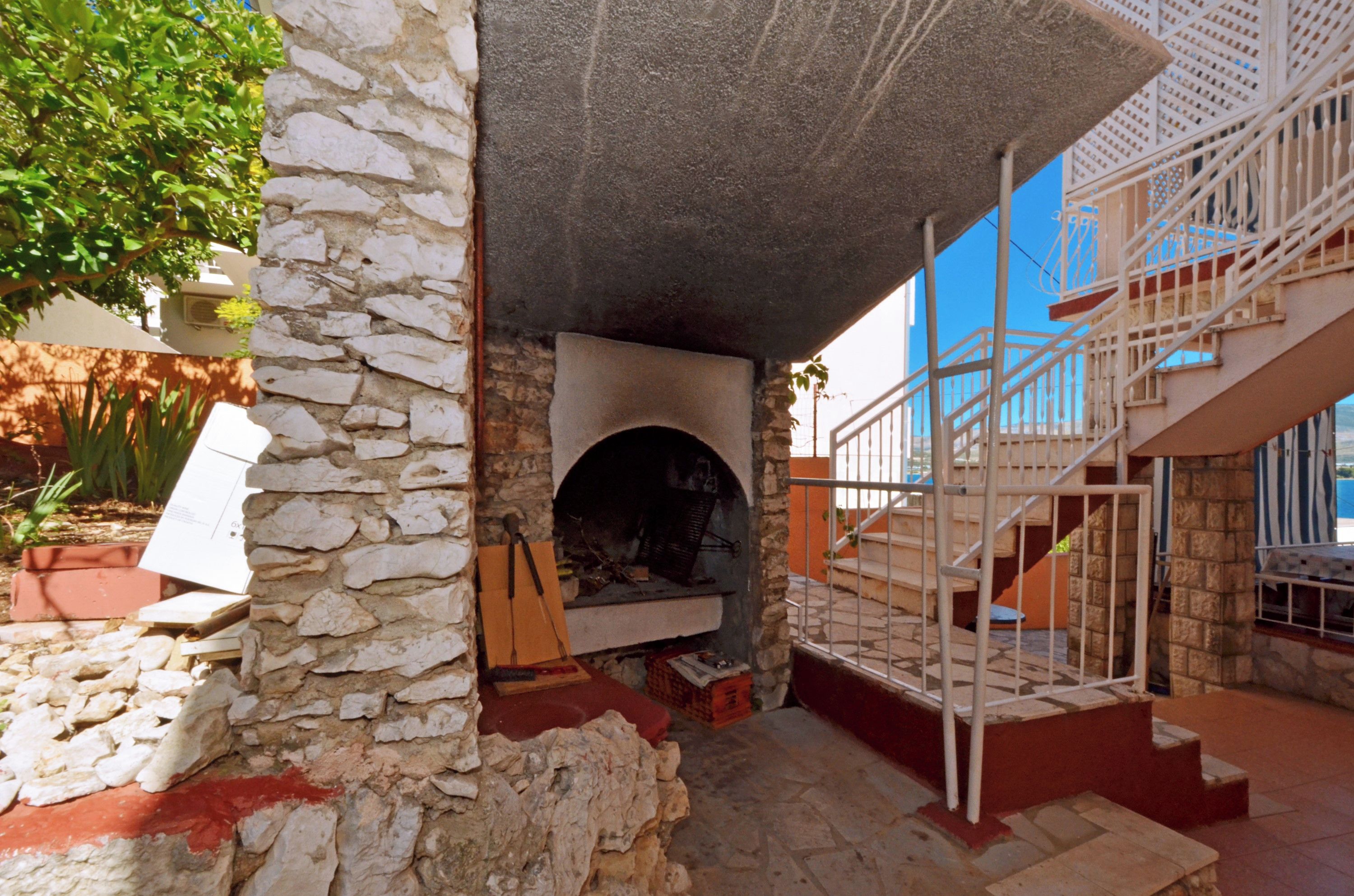 A stone fireplace with a wooden bench, a staircase, and a view of the sea.