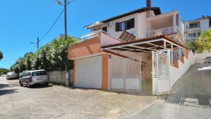 Een twee verdiepingen tellend huis met garage, balkon en een helderblauwe lucht.