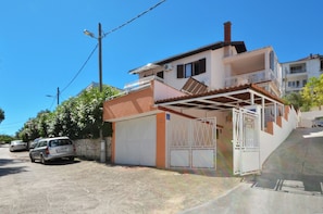 Uma casa de dois andares com garagem, varanda e um céu azul claro.