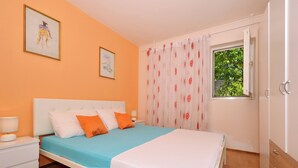 Een slaapkamer met een bed, nachtkastjes, een raam met gordijnen en kunst aan de muren.