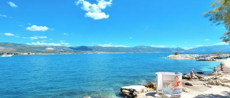Vista costera con aguas azul cristalino, costa rocosa y montañas al lejano.
