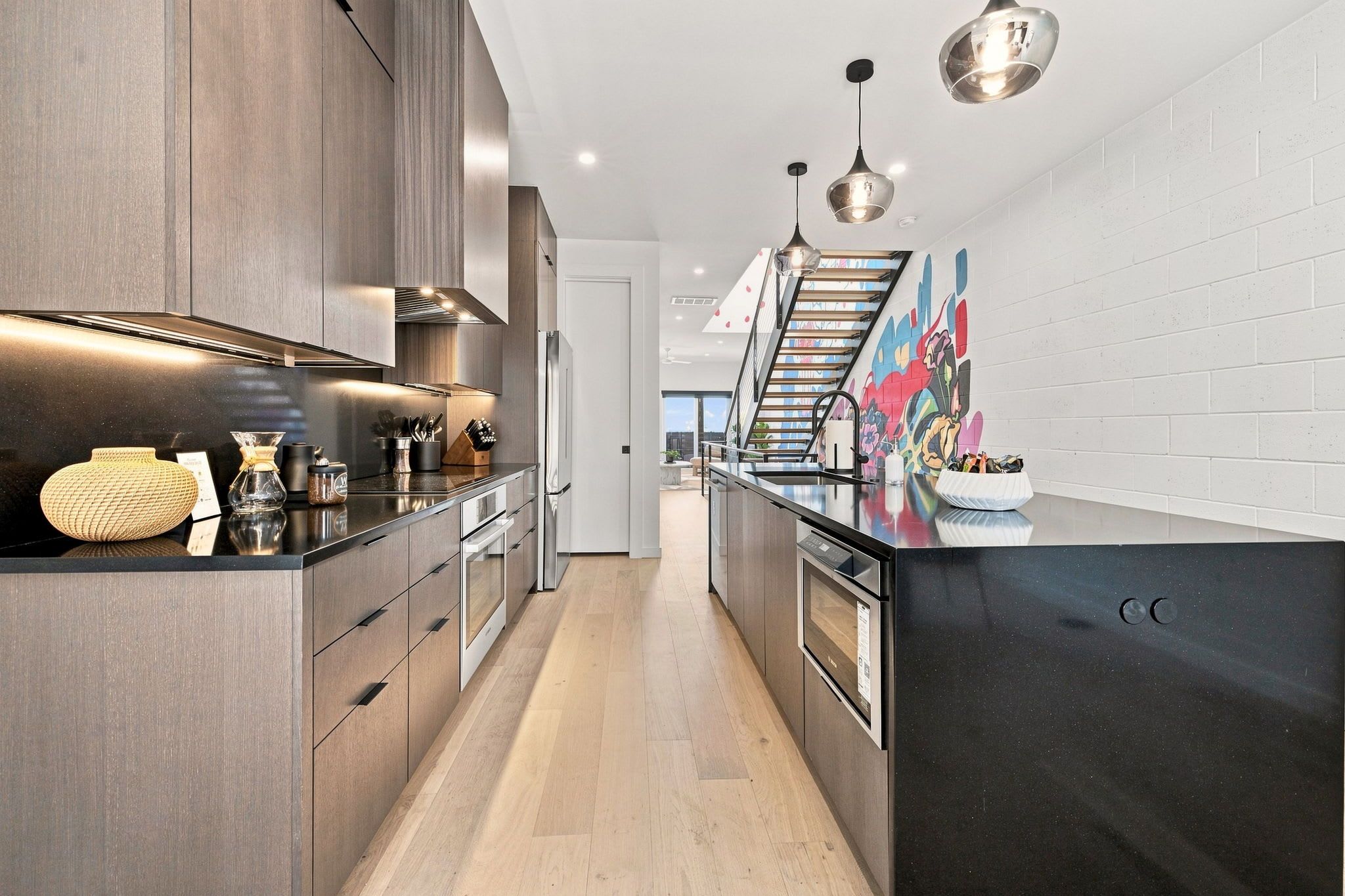 A modern kitchen with dark wood cabinets, stainless steel appliances, and a black countertop.