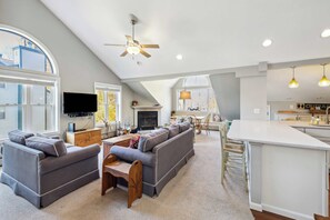 A spacious living area with a large sofa set, a television, and a fireplace. - Okemo Winterplace 2BR Loft – Family Ski Getaway (Ludlow)