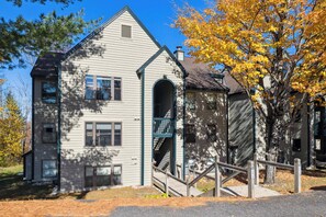 A two-story building with a central arched entrance and a small porch. - Okemo Winterplace 2BR Loft – Family Ski Getaway (Ludlow)