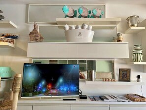 Ein modernes Wohnzimmer mit Flachbildfernseher, Dekorationsgegenständen und einem weißen Konsolentisch.