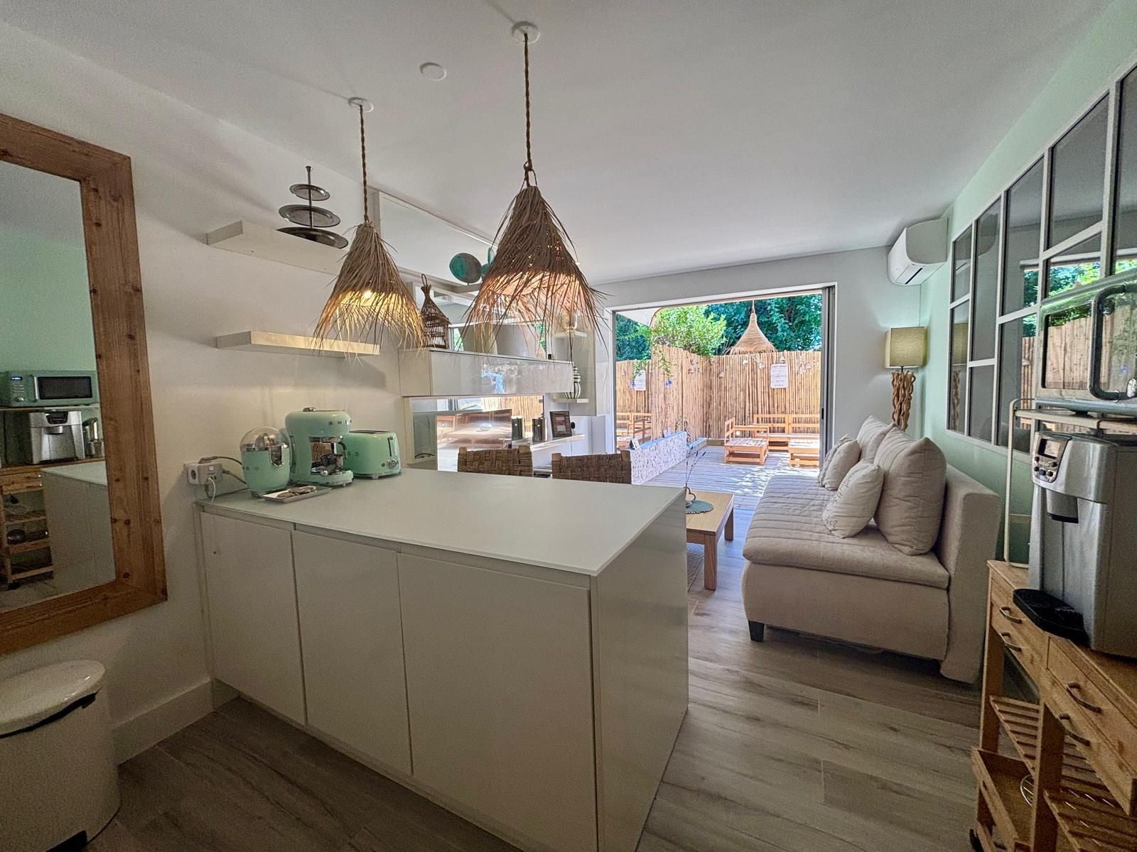 A modern kitchen with a central island, pendant lighting, and a view to an outdoor seating area.