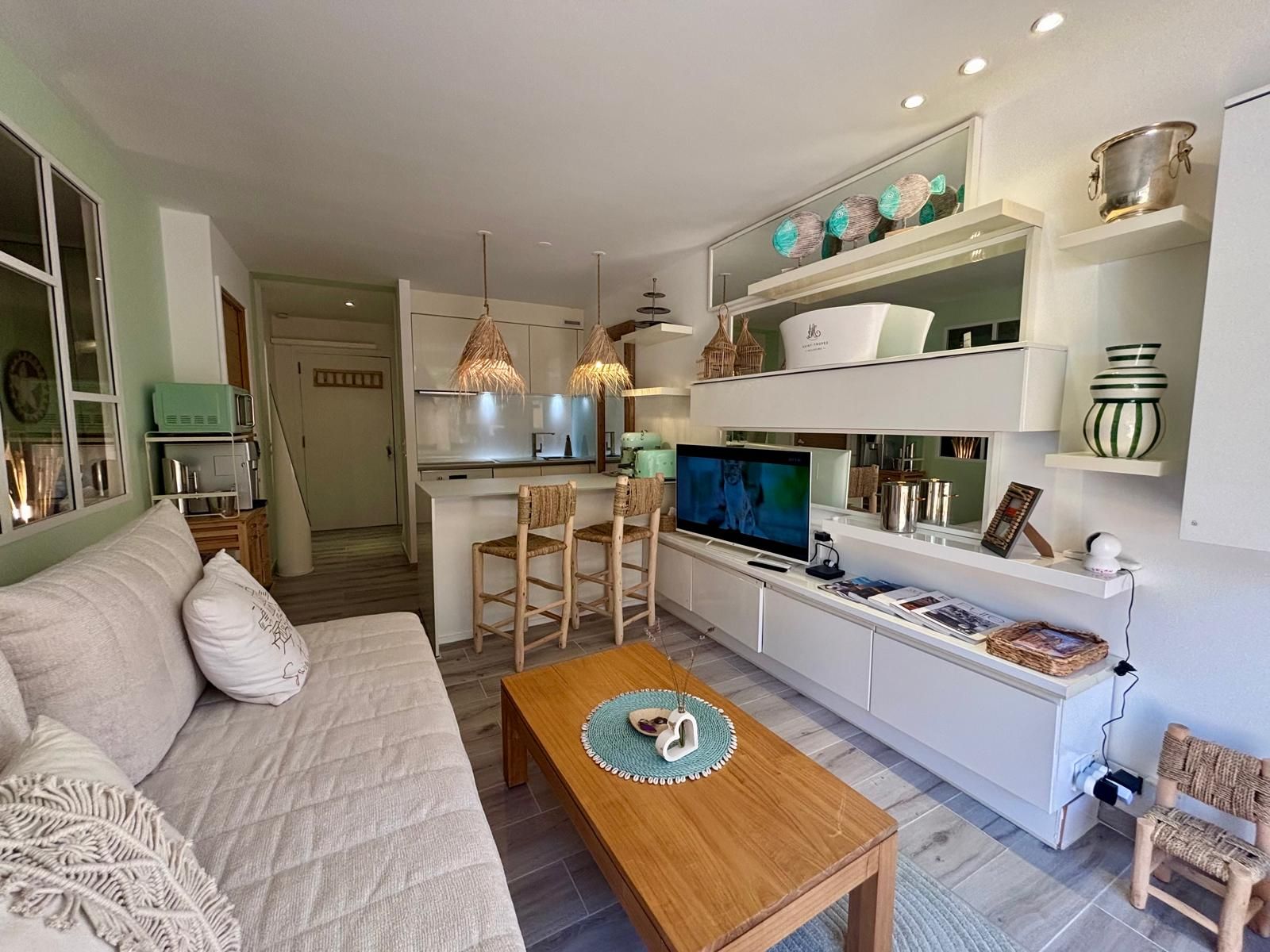 Una sala moderna con sofá, mesa de centro, televisor y área de cocina con comedor.