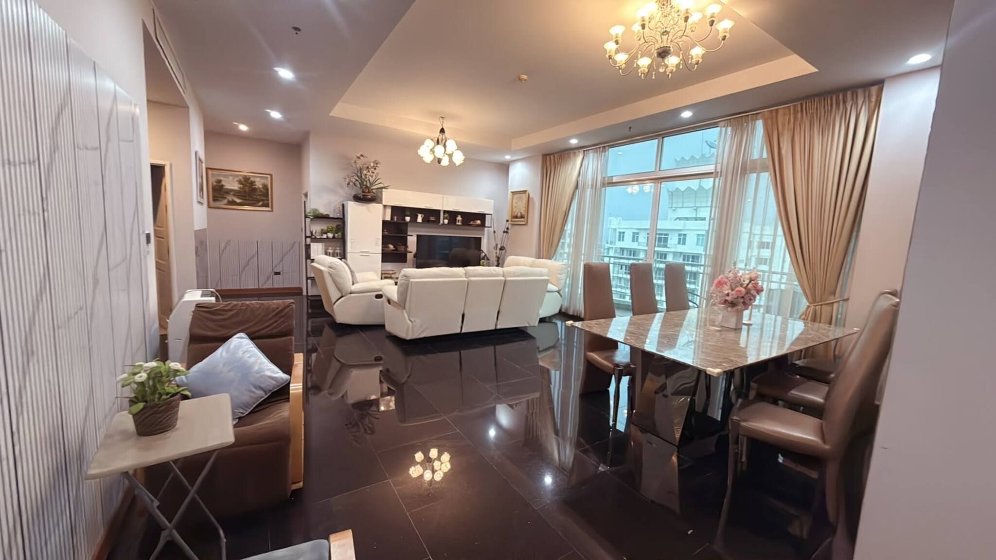 A modern living room with a dining area, a sofa, a coffee table, and a chandelier.