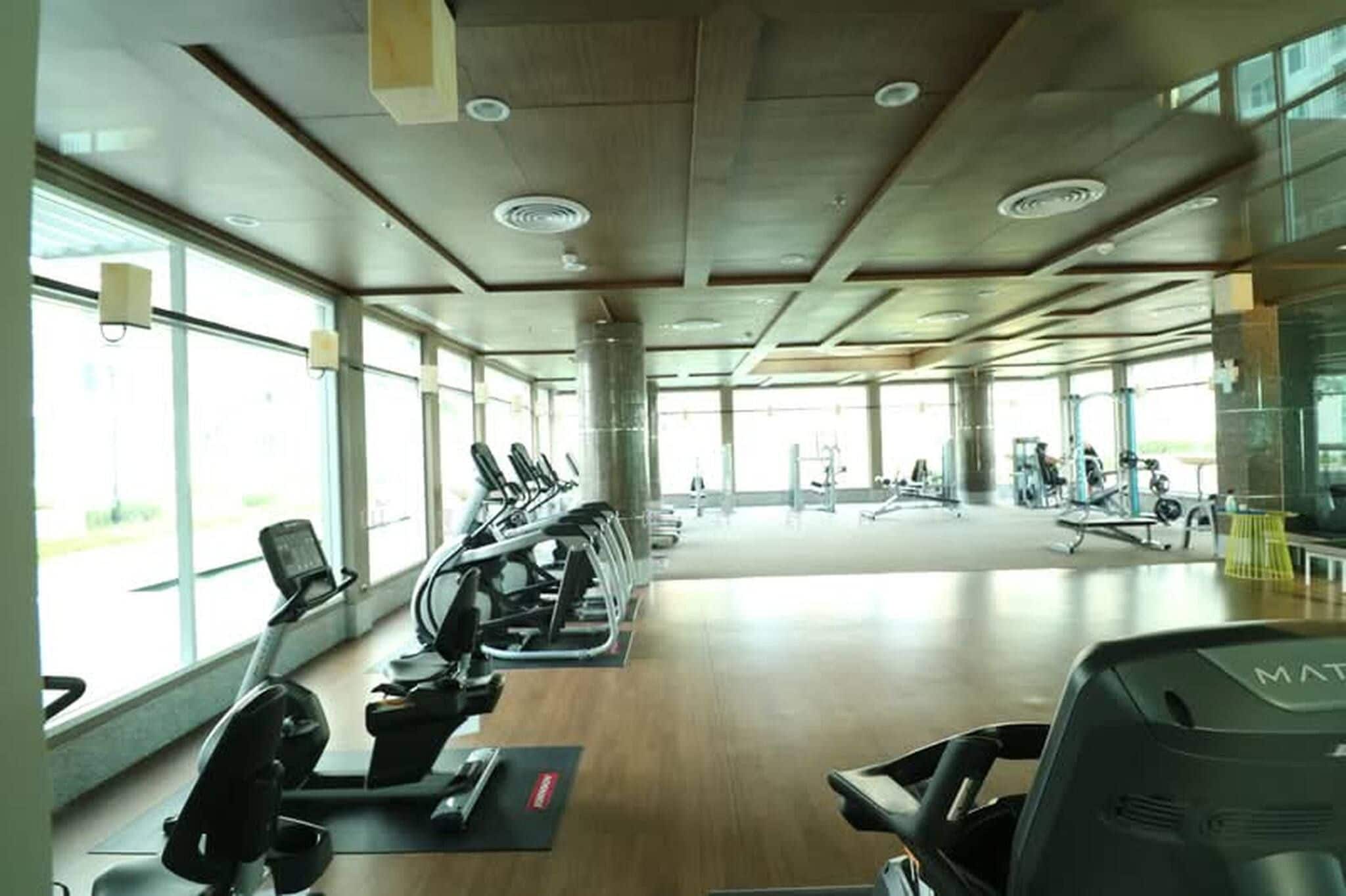 A gym with exercise equipment, large windows, and a spacious layout.
