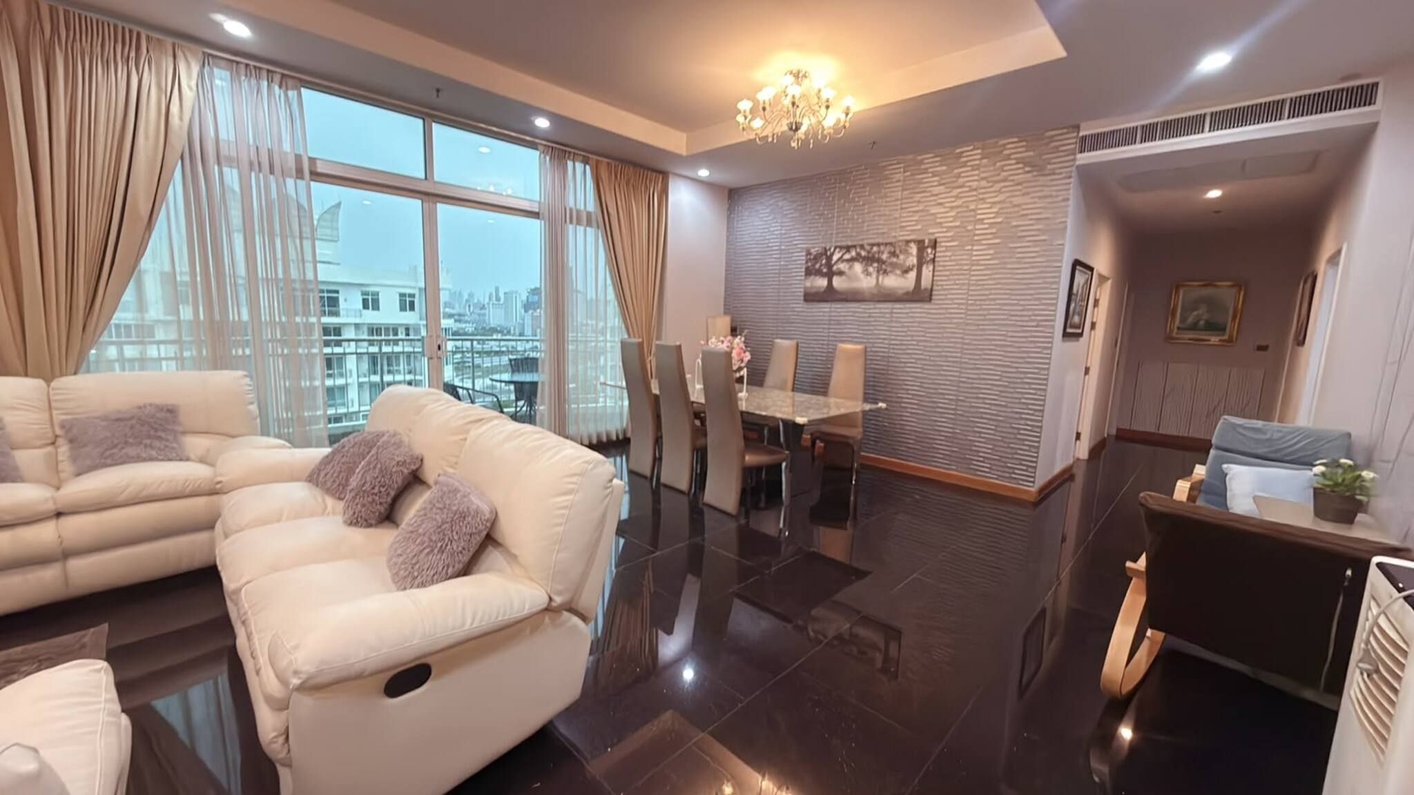 A modern living room with a sofa, dining area, and a view of the cityscape.
