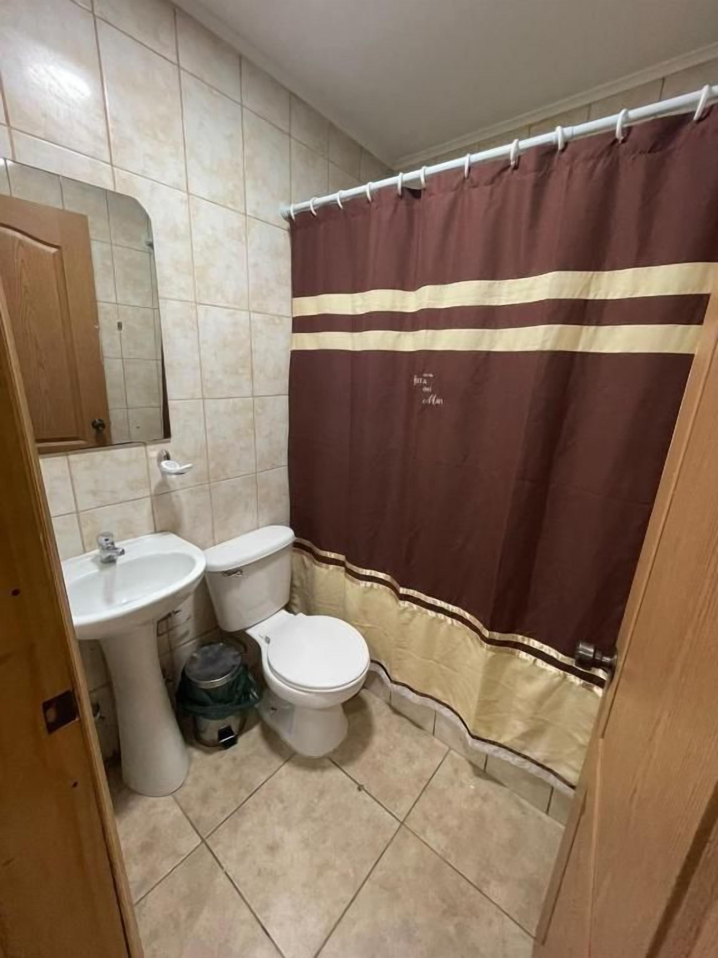 Un baño con inodoro, lavamanos y cortina de ducha.