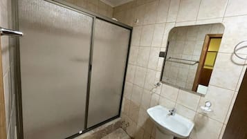 Un baño con cabina de ducha, lavamanos y espejo.