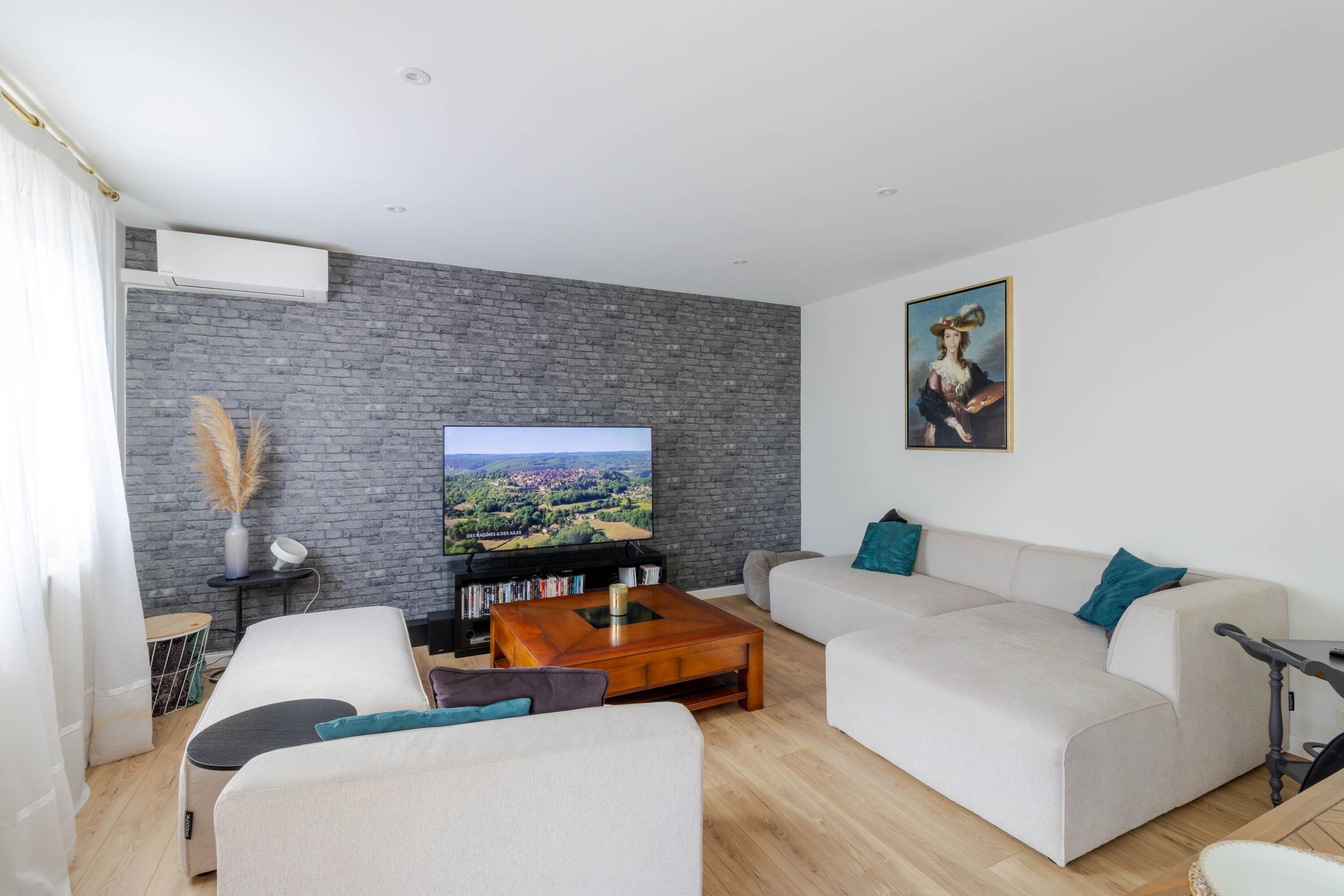 Ein modernes Wohnzimmer mit Flachbildfernseher, einer Sofagarnitur, einem Couchtisch und einem Bücherregal.