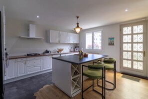 Una cocina moderna con armarios blancos, una isla central y una zona de comedor con taburetes verdes.