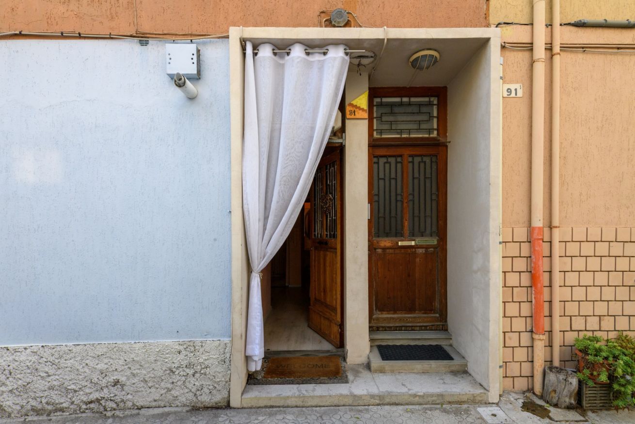 A doorway with a wooden door, a metal gate, and a white curtain.