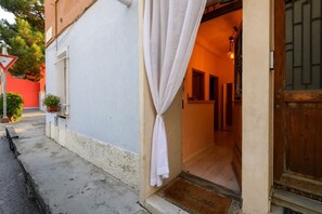 Ein Hotel Eingang mit weißem Vorhang, rotem Tür und einer 'WELCOME'-Fußmatte.