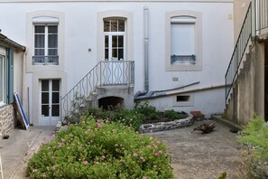 A building with a central staircase, a small balcony, and a flower bed in the foreground. - La Perle de Bon Secours - à 200 m de la plage (Saint-Malo)